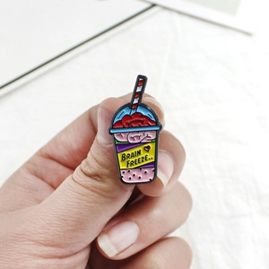 Close-up of a creative enamel pin showing a brain freeze drink with pink brain detail