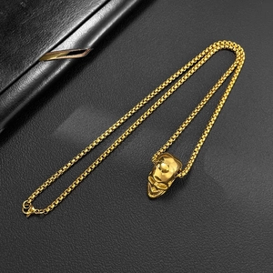 Close-up of golden skull pendant with polished finish on black leather texture