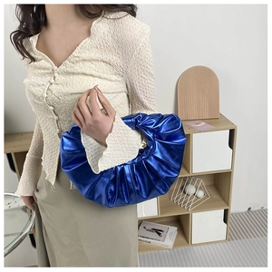 Detail der elektrisch blauen Metallic-Handtasche mit Falten in Halbmondform