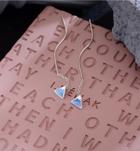 Detailed view of silver mount fuji style earrings with blue enamel on a pink background