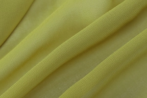 Close-up of light yellow-green chiffon fabric texture showing weave and draping