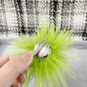Detail of the silver dual-use alligator clip and pin back on a neon green feather brooch