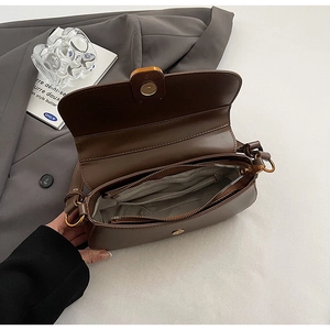 Detail view of the brown saddle bag interior with a zipper pocket and smooth PU leather