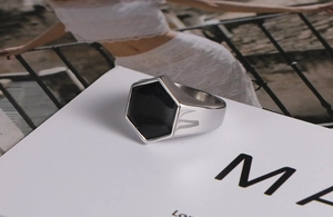 Dettaglio macro di un anello a sigillo esagonale in acciaio inox con intarsio nero