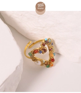 Close-up of gold heart-shaped ring with colorful beads and natural freshwater pearl