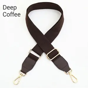 Detail of dark coffee canvas shoulder strap with gold metal hooks and leather joints
