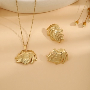 Detailed view of luxury gold necklace and earrings with textured feather leaf design