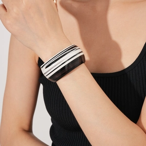 Close-up of black and white striped acetate cuff bracelet worn on woman's wrist