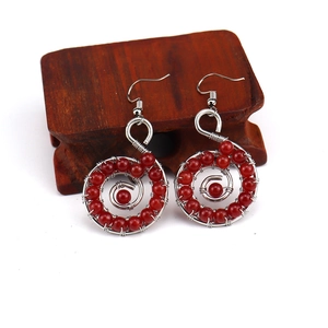 Macro shot of handmade silver wire wrapped earrings with red gemstone beads on a wooden stand