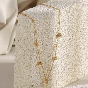 Detail of 18K gold-plated necklace with three zircon stones draped over a textured stone