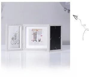Detail of light wood grain triple folding picture frame with metal hinges on white table