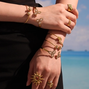 Golden teardrop petal cuff bracelet with zircon inlays styled on a tropical beach