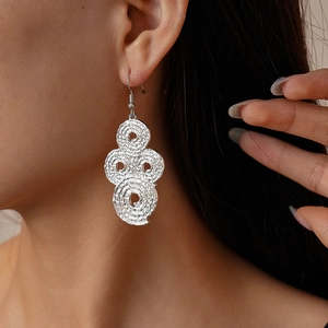 Detail of silver-toned crumpled metal hoop earrings on model showing minimalist texture