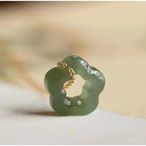 Macro shot of green jade flower pendant on a fine gold necklace with elegant details