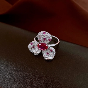 Macro detail of a silver flower ring with red gemstone and sparkling zirconia pavé