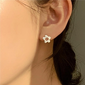 Close-up of minimalist 925 silver flower stud earring on a model's ear