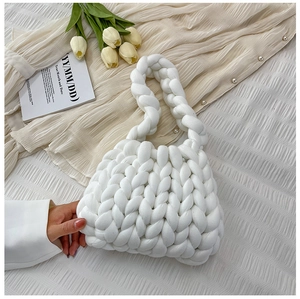 Detail of white chunky yarn woven handbag with thick braid design held by a model
