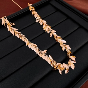 Close-up of golden leaf-shaped sequins on a necklace displayed on a black jewelry tray