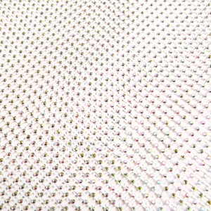 Gros plan sur un tissu en maille blanche orné de strass colorés pour robe de soirée