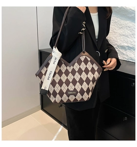 Macro detail of diamond quilted knit tote bag with decorative brand ribbon and leather trim