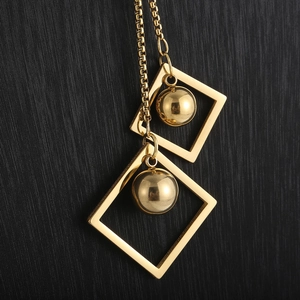 Macro shot of gold square frames and round beads pendant on a fine box chain