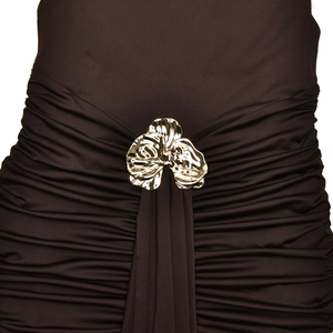 Detail of ruched brown fabric with a gold flower brooch on a summer maxi dress