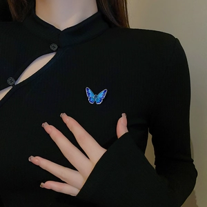 Detailed shot of gradient blue butterfly brooch with silver edges on black knitwear