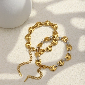 Primer plano de pulsera de cadena con corazón bañada en oro 18K sobre piedra natural