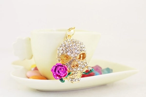 Close-up of sparkling rhinestone skull keychain with a purple rose on a cup edge