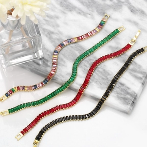Detail of colorful baguette cut zircon tennis bracelets in gold plating on marble surface