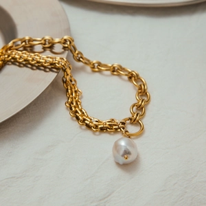 Detailed close-up of a layered gold necklace featuring a unique baroque pearl pendant