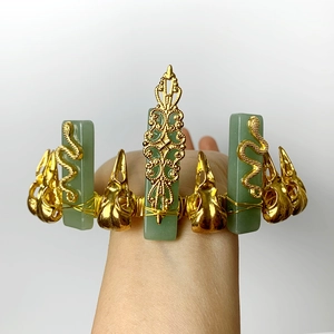 Golden woven bracelet with green stones and skull charms on a model's wrist
