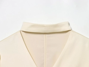 Dettaglio dell'elegante camicetta in raso beige con scollo a V e colletto a sciarpa