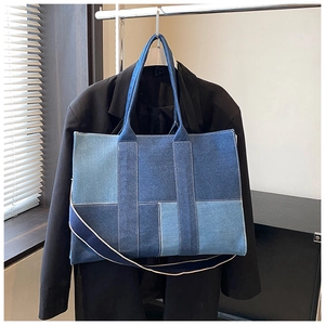 Detail of blue denim patchwork tote bag with extended handles and spacious rectangular shape