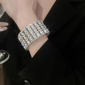 Macro shot of a 6-row silver-tone crystal elastic bracelet on a black suit sleeve