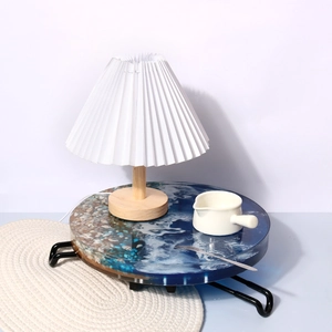 Detail of round ocean resin table with blue waves, real pebbles and black metal legs
