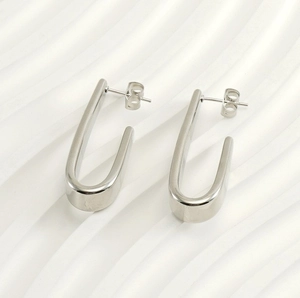 Vue détaillée de boucles d'oreilles en acier titane argenté en forme de U sur fond texturé