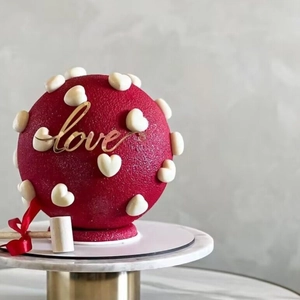 Gros plan d'un gâteau rose en forme de cœur avec cœurs blancs et décor Love
