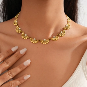 Gros plan d'un modèle portant un collier doré en forme d'éventail serti de strass brillants