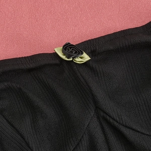 Macro detail of satin rose applique on black ribbed knit fabric neckline