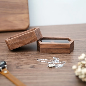 Macro shot of hexagonal walnut wood jewelry box with flip-top lid on textured wood surface