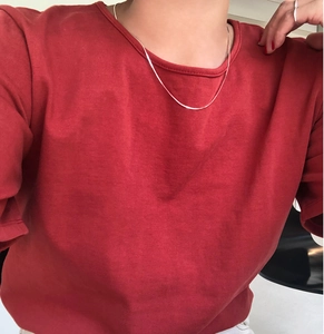 Close-up of minimalist 925 sterling silver snake chain worn on a red cotton shirt