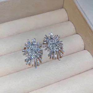 Elegant silver starburst earrings with sparkling crystals displayed in a beige jewelry box