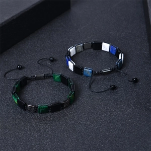 Detail of adjustable woven bracelets with green and blue square stones on black background