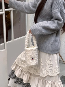 Detail of white plush handbag featuring a cute black cat patch and soft wool-like texture