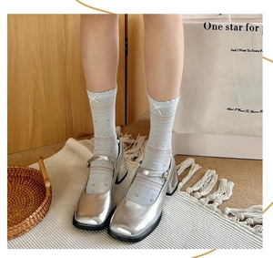 Close-up of light blue mesh crew socks with white bows and silver Mary Jane shoes