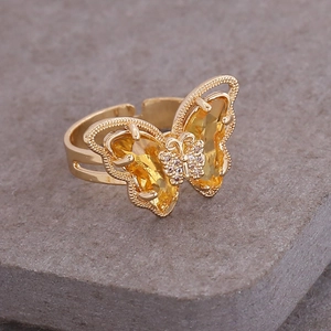 Macro detail of 18K gold butterfly ring featuring yellow gemstones and clear crystals