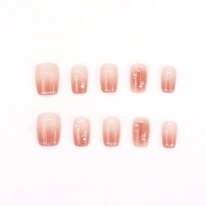 Faux ongles faits main dégradé rose avec perles et strass sur fond blanc épuré