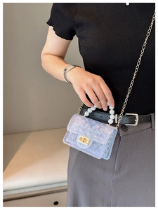 Close-up of iridescent jelly bag featuring pearl handle and gold rotary lock detail