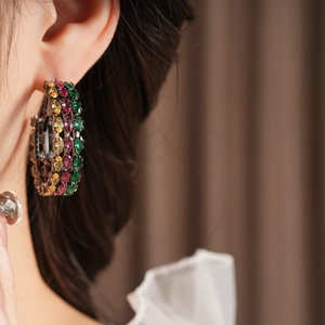 Close-up of vintage hoop earrings with yellow, red, and green cubic zirconia gemstones